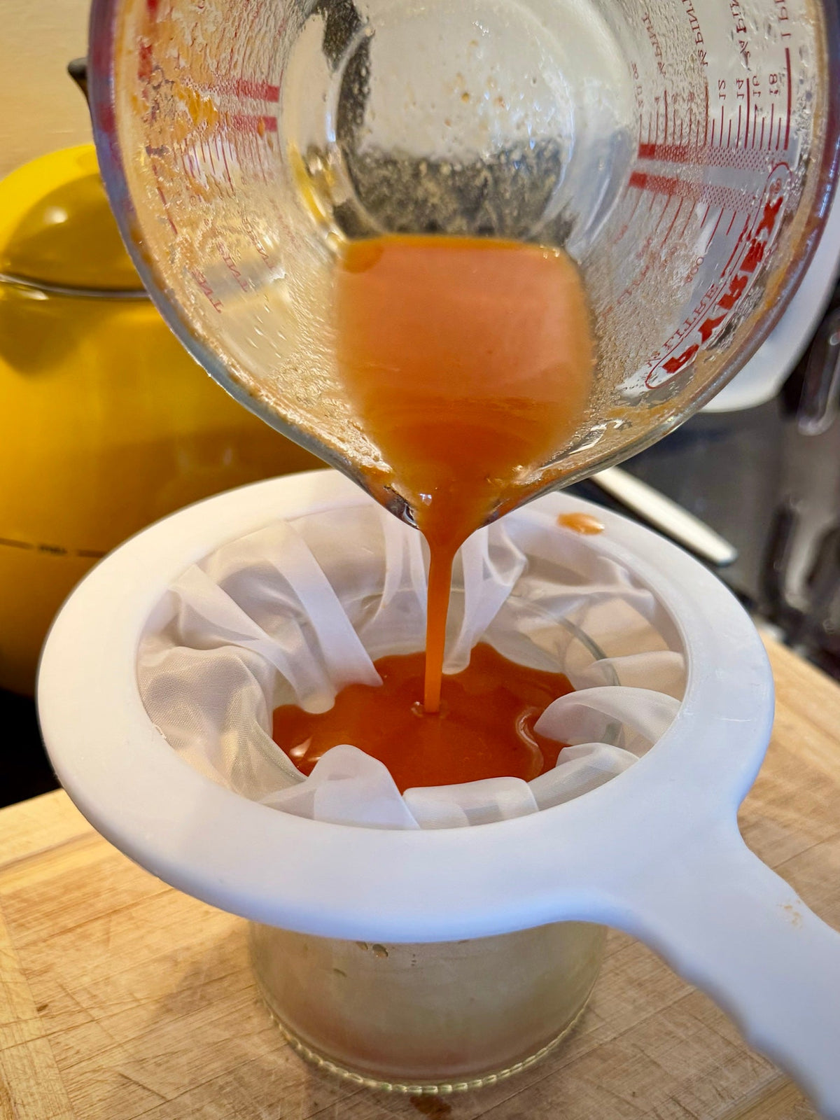 Pouring simmered rowan berry ink through muslin into a jar