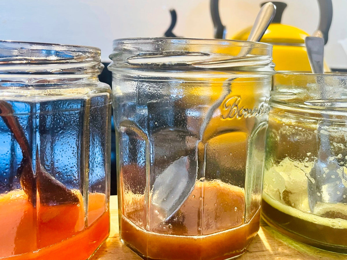 Three jars of rowan berry ink on the kitchen counter: coral, tan and olive, one berry with different things stirred in
